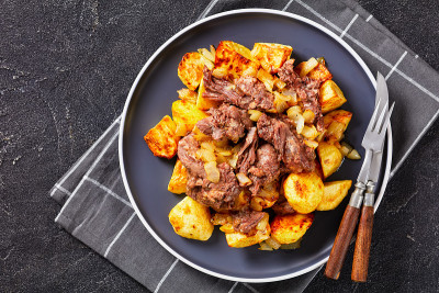 炖牛肉，洋基炖牛肉，土豆和洋葱放在一个盘子里放在混凝土桌子上，美式烹饪，平放，自由空间，特写