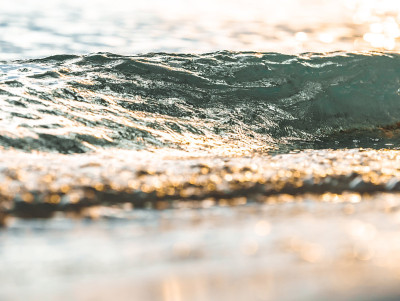 特写动作美丽的海浪在海滩上，而日落。主题是模糊的