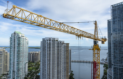 在迈阿密市中心的摩天大楼建筑工地上，起重机高高悬挂在天际线上