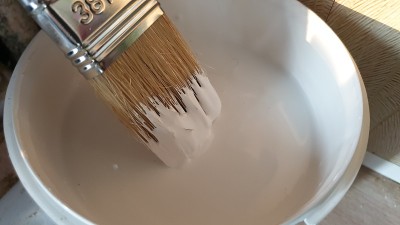 刷白漆。一桶用刷子刷的白漆。