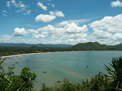 船航行在绿色的水与蓝色的天空和蓬松的云在背景
