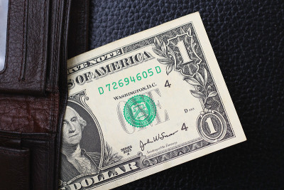 1 dollar from a brown wallet on a black leather