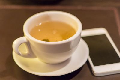 桌上放着一杯绿茶和一个白色的电话