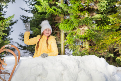 快乐的女孩从雪塔上扔雪球