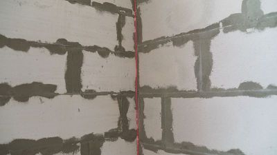 建筑工在建筑工地用激光水平仪进行安排。建筑激光水平仪和墙壁表面标记的红线。激光水平对砌块墙