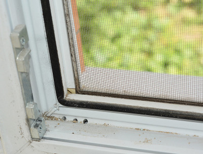一个打开的upvc / pvc窗框的特写，安装了橡胶密封，锁辊和防蚊纱窗，脏的窗轨被灰尘覆盖，需要清