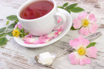 一杯茶和野玫瑰花在旧木板上