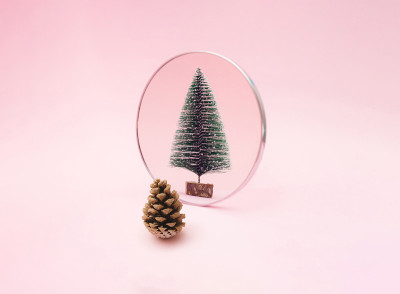 松果照镜子，见新年绿雪树。粉色柔和的背景。最小假日设计和概念。