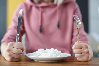Woman holding fork and knife in hands near plate w
