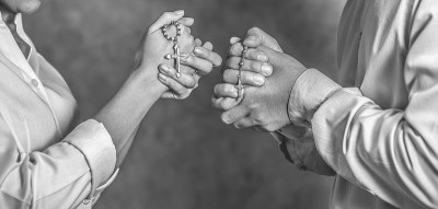基督教黑白背景双手捧着十字念珠祈求上帝祝福。基督教观念是人们的信仰和实践