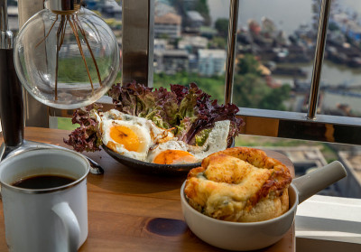 阳台木桌上的早餐:菠菜奶油蛋卷，两个煎蛋，橡木叶生菜配黑咖啡。