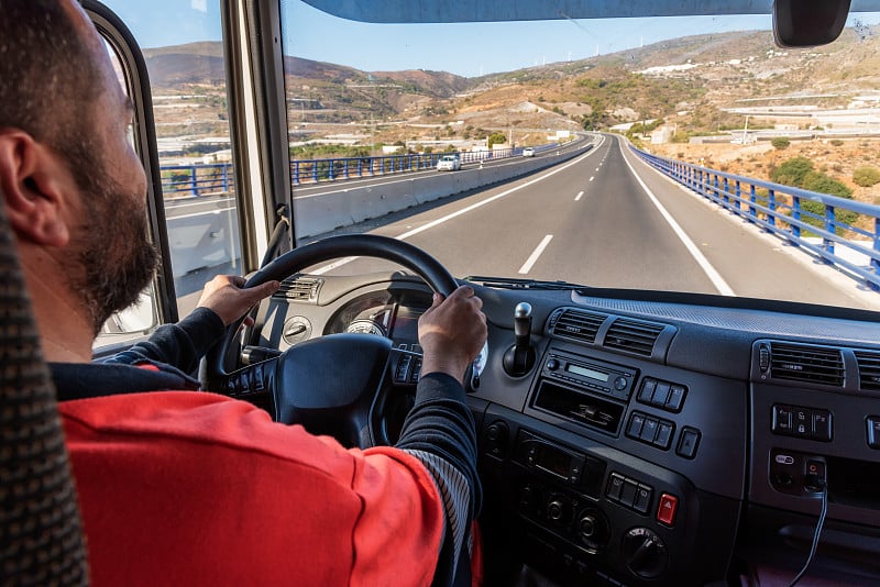 从驾驶室里看，卡车司机在高速公路上开车。