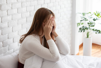 亚洲年轻女性有偏头痛和头痛早上醒来后，保健概念