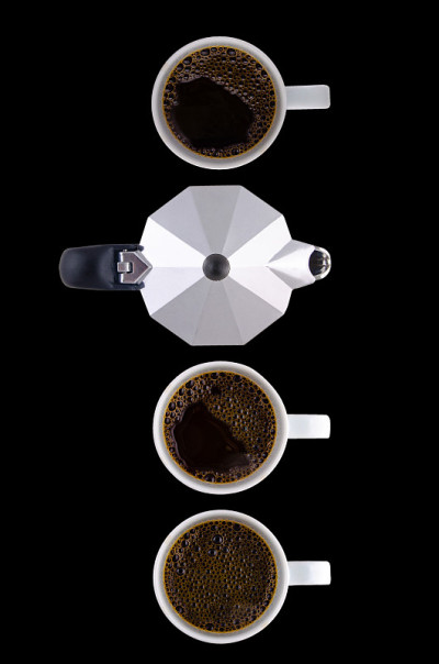 coffee pot and three white cups on a black backgro
