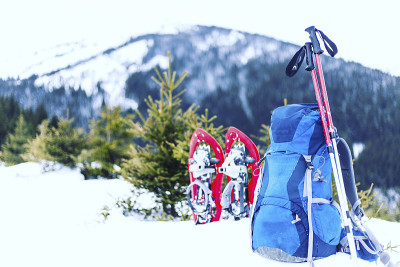 冬天在山上徒步旅行，穿着雪鞋，背着背包和帐篷。