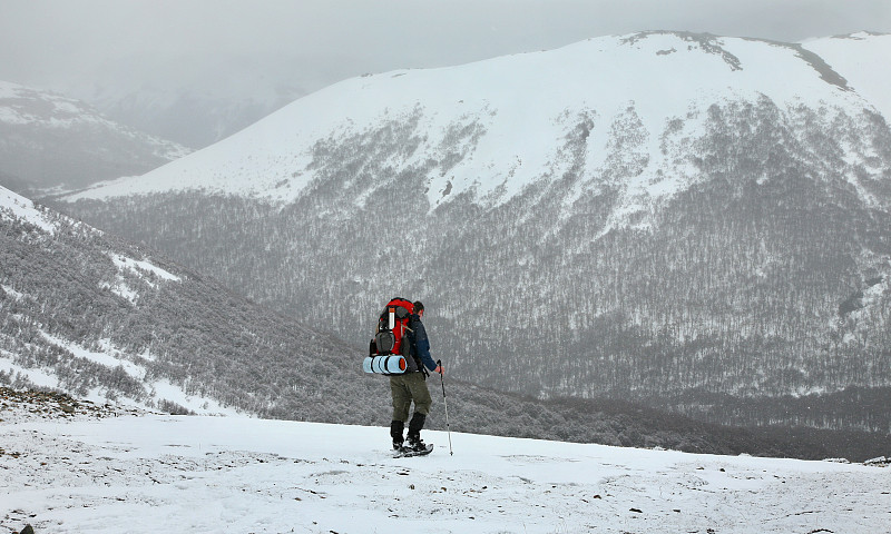 一个孤独的徒步旅行者在一个白雪皑皑荒凉的荒野山谷