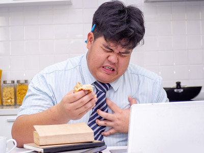 亚洲胖男人吃东西时感到心痛。心脏病发作，胸痛的男人。