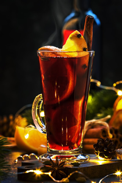 圣诞热红酒，香料和水果在高脚杯，在木制的乡村桌子。传统的圣诞热饮在节日的餐桌设置