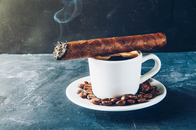 一杯咖啡，咖啡豆，烟灰缸和雪茄在黑暗的背景