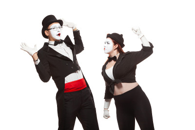 两个哑剧演员的肖像表演，孤立在白色的背景。女人对那个男人举起了拳头。象征着争斗，争吵，家庭问题，家庭
