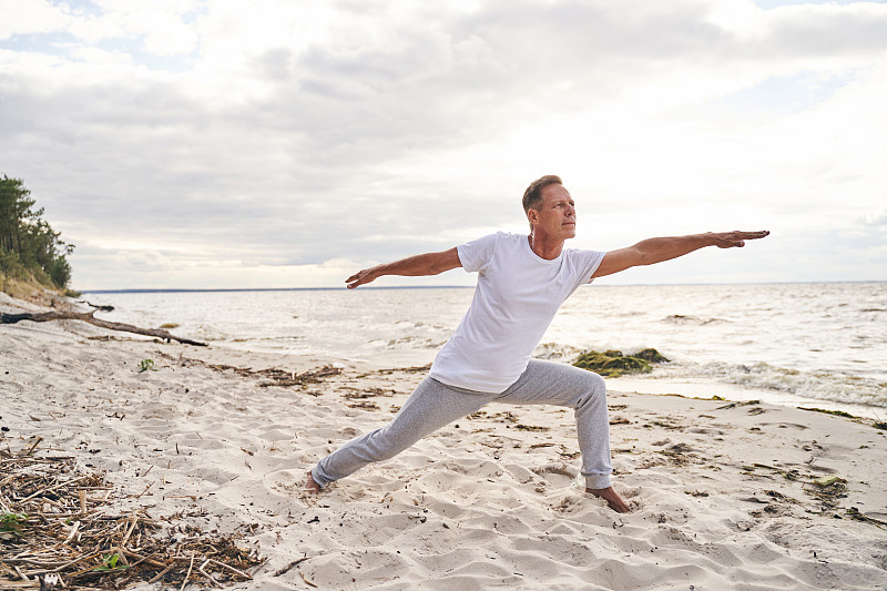 Calm mature male doing eastern practice in beach