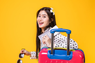 夏日休闲装的女游客。亚洲微笑女子。以黄色为背景出国旅行的乘客。一个亚洲女人要去度暑假。旅行有趣的旅行