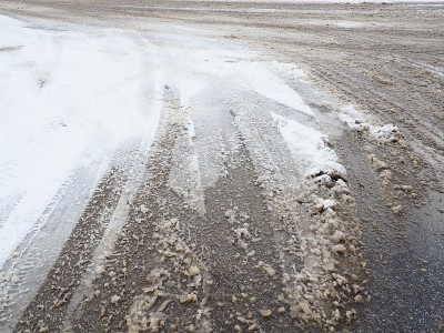 岔路口回旋处的叉或侧板路边积着雪堆。坏天气。雪在沥青。困难的驾驶和交通状况。路上冬天的雪泥。汽车制动
