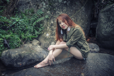 亚洲美丽的年轻女孩坐在岩石上