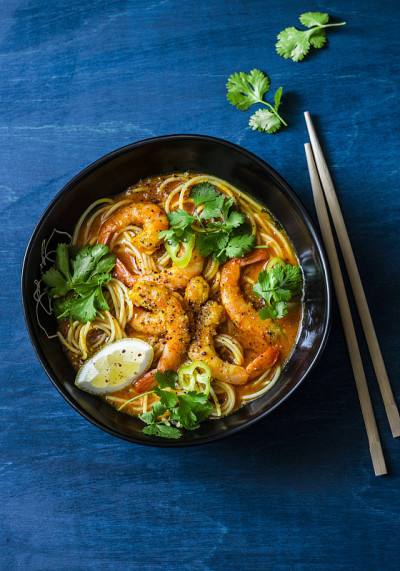 蓝色背景上的椰虾叻沙汤，俯视图。副本的空间。亚洲风格的食物