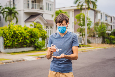 一个小镇上的男子戴着医用口罩，因为冠状病毒正在流行，他正在使用消毒剂