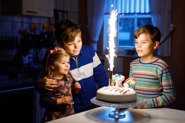 可爱的蹒跚学步的小女孩庆祝三岁生日。小妹妹孩子和两个小男孩兄弟一起吹蜡烛上的蛋糕。幸福健康的全家福和