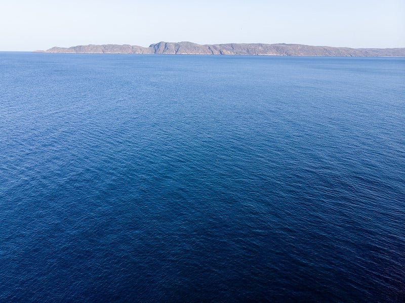 俯视图航空照片从飞行无人机一个惊人的美丽的海景，蓝色的水，岩石海岸线。巴伦支海。秋天在苔原上，阳光明