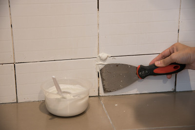 DIY。用镘刀修补墙壁上的瓷砖，清除空隙缝中残留的胶水，安装新的胶水或白色硅胶，铺砖和饰面技术。