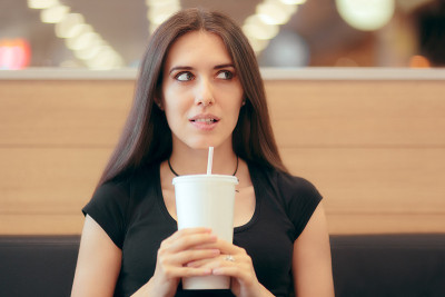 拿着一次性苏打杯的女人在快餐店里等着