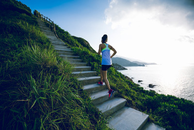 坚定的女子超级马拉松运动员在海边的山楼梯上奔跑