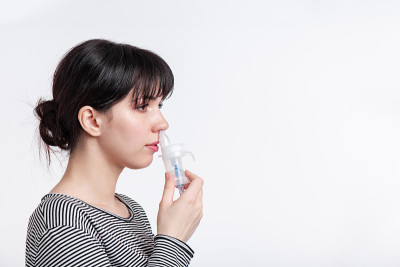 头像的黑发女人使用鼻吸入器。病人吸入药物