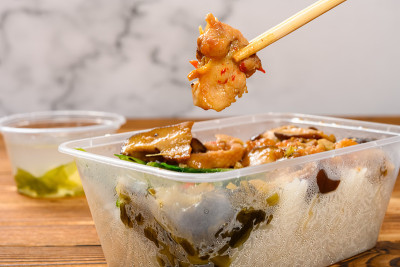 筷子从快餐盒中夹起一块鸡肉