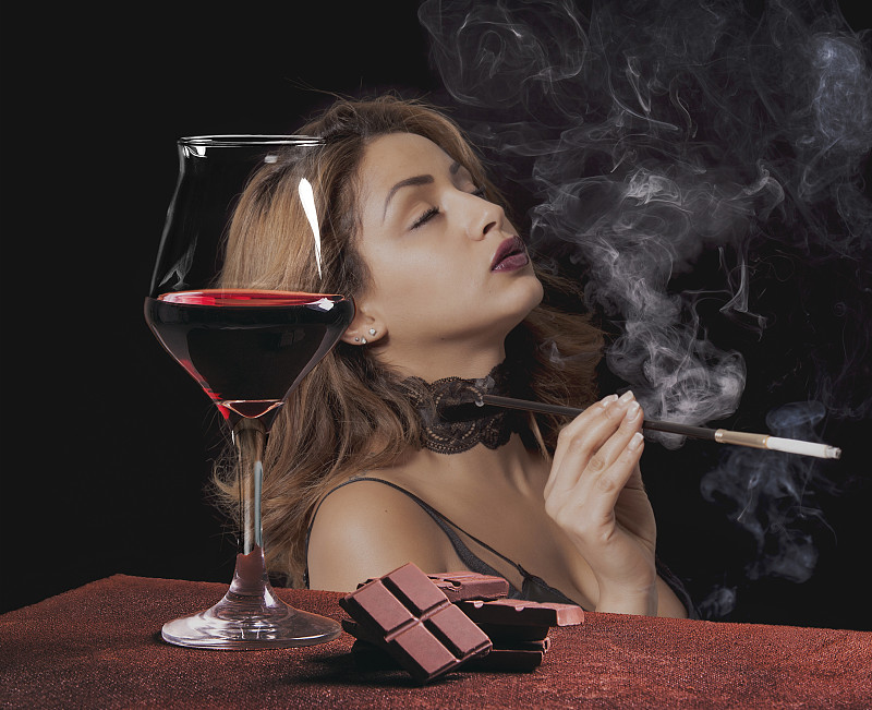 带巧克力的红酒杯和抽烟的女人肖像