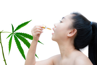 在白色背景下，手持舌下滴管大麻油的女子