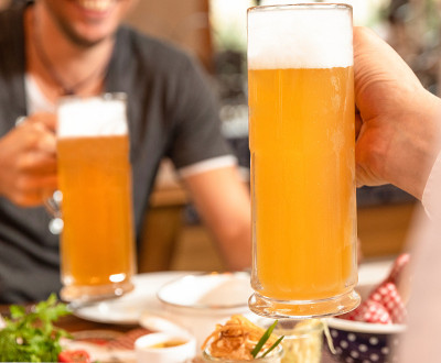 两个人拿着啤酒杯，桌上放着零食