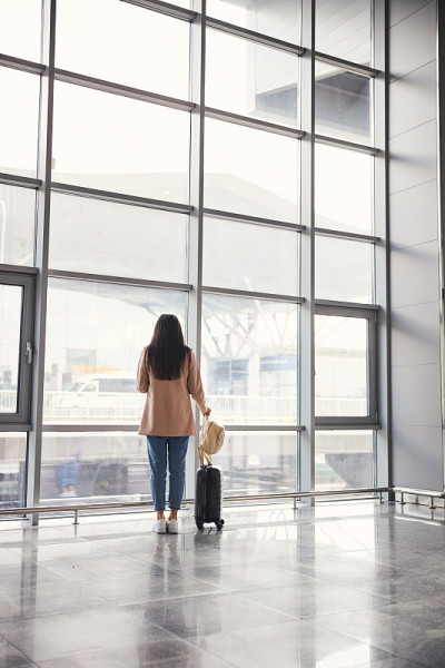 优雅的女士拿着旅行箱站在机场候机楼