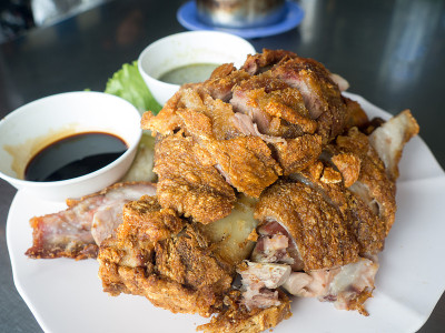 香酥炸猪腿放在盘子里，配上蔬菜和调味汁