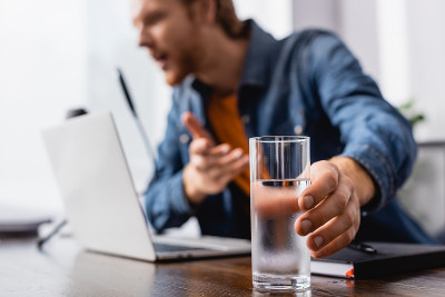 有选择的焦点播音员拿着一杯冷水在麦克风讲话