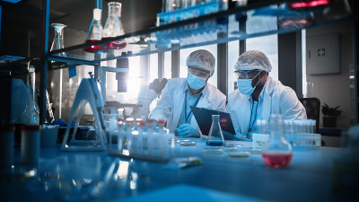 现代医学研究实验室:两名科学家戴着口罩使用显微镜，在培养皿中分析样品，探讨创新技术。医学、生物技术先