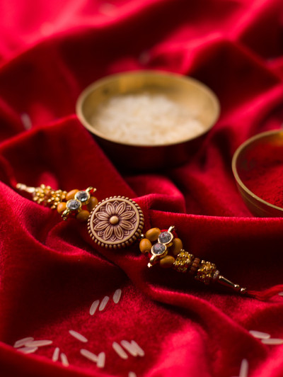 Raksha Bandhan背景以优雅的Rakhi和米粒在红布纹理背景。