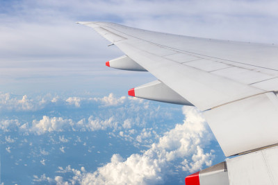 飞机机翼窗外多云的天空背景，旅游度假概念