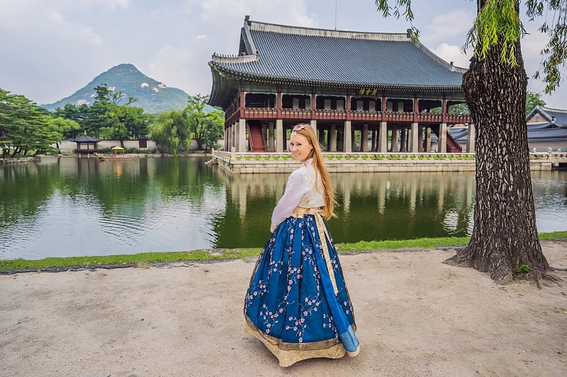 身穿韩服的年轻白种女游客在韩国宫殿。韩国旅游概念。国家韩国的服装。为游客提供的娱乐——试穿韩国民族服