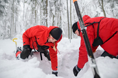 冬季在户外森林里用铁铲挖雪，开展山地救援服务。