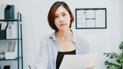 亚洲女商人在新常态下保持社交距离以预防病毒在办公室工作时看着摄像机向朋友介绍计划视频通话。
