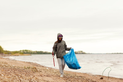 Young female environmental volunteer in cap and ho